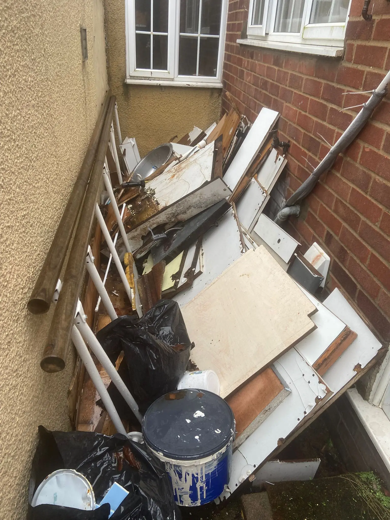 Cluttered side alley piled with household waste before clearance